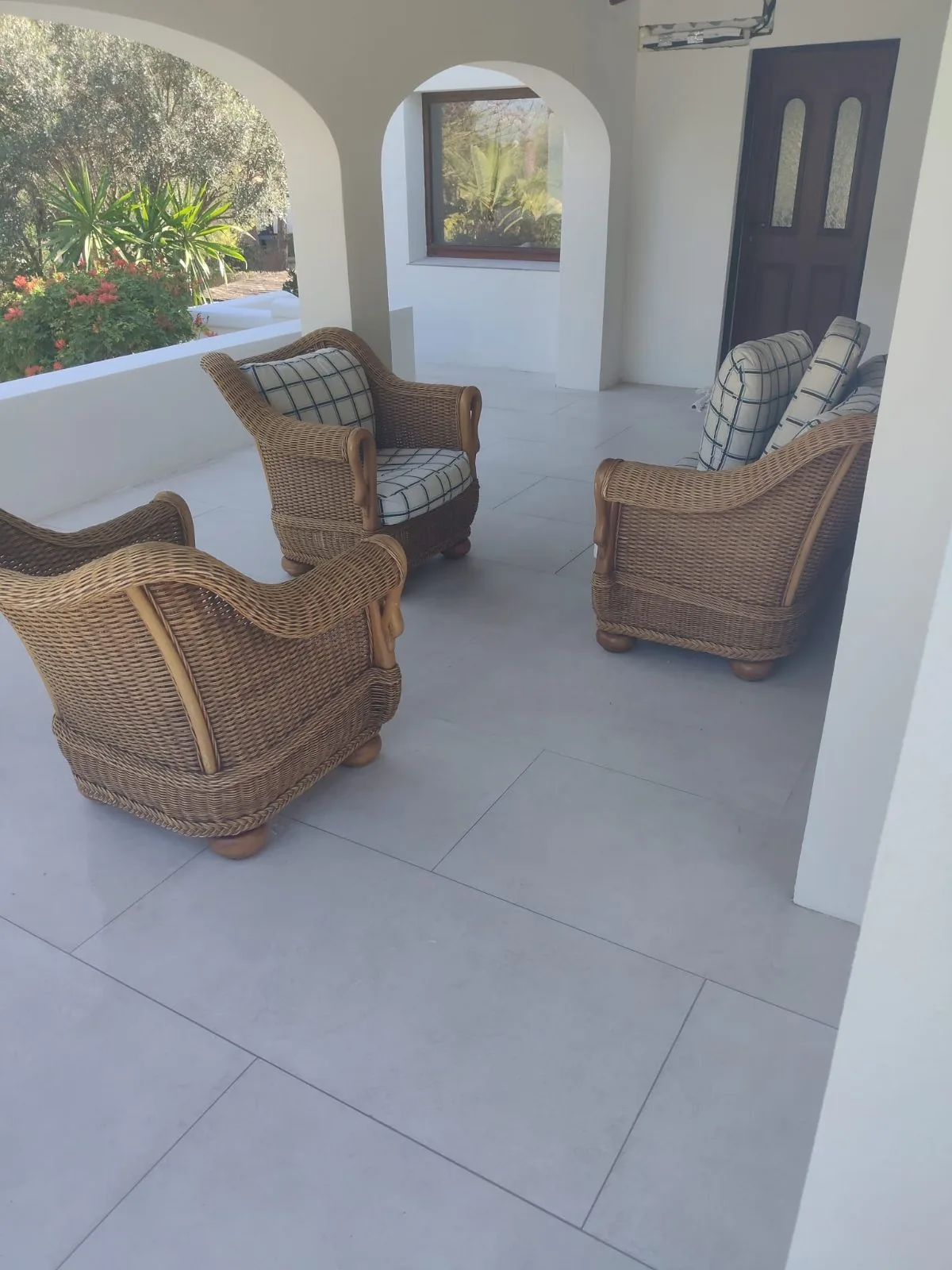 Porche con arcos y suelo de gres claro nuevo con sillones de mimbre
