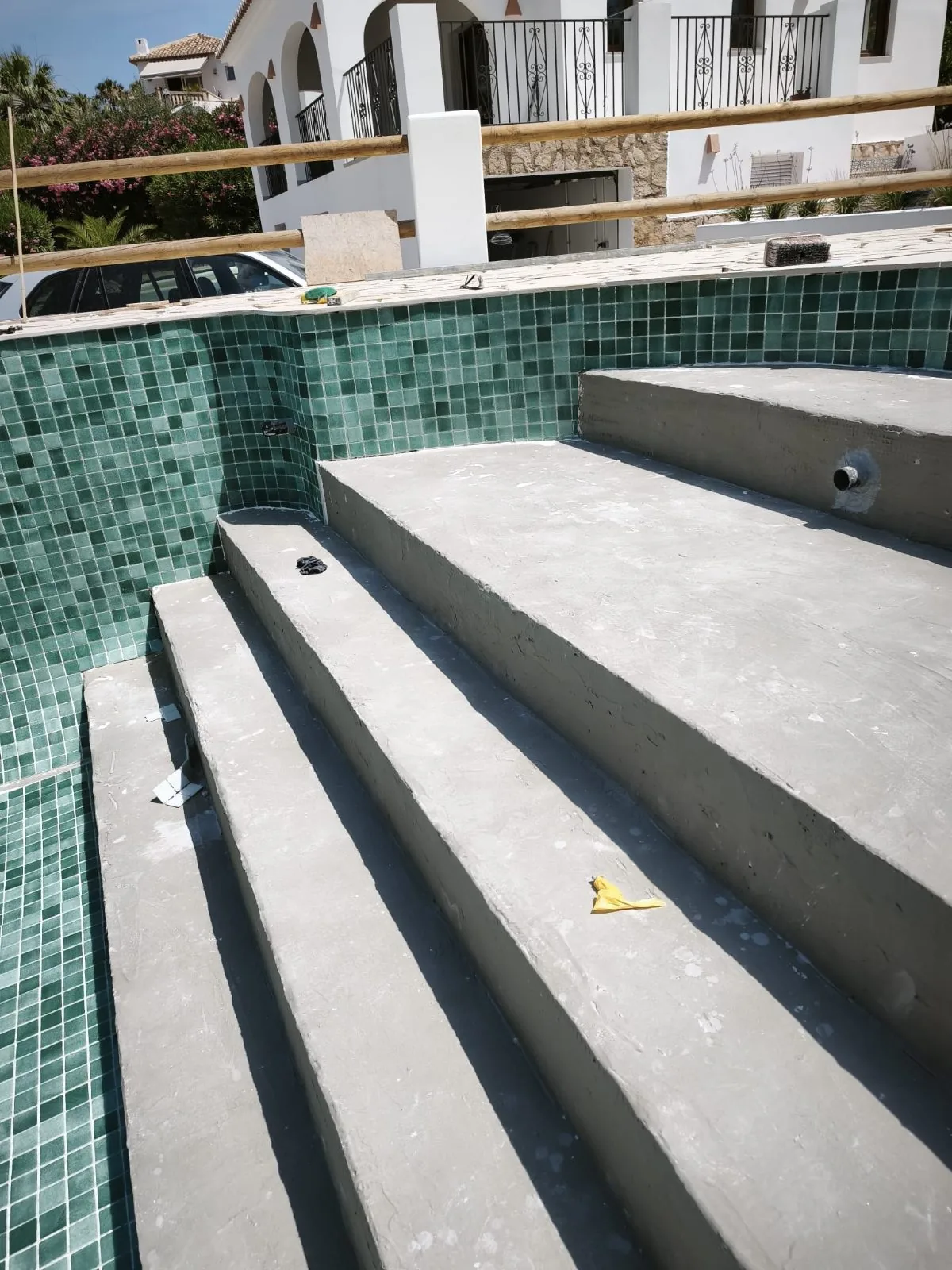 Escalones de hormigón de una piscina con paredes de mosaico verde ya colocado