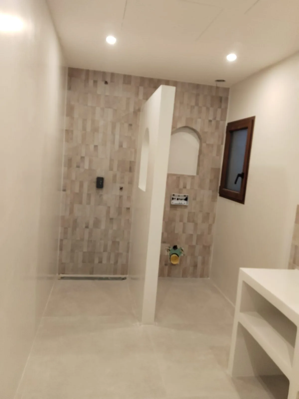 Baño terminado con ducha a ras de suelo, pared alicatada y mueble de obra blanco