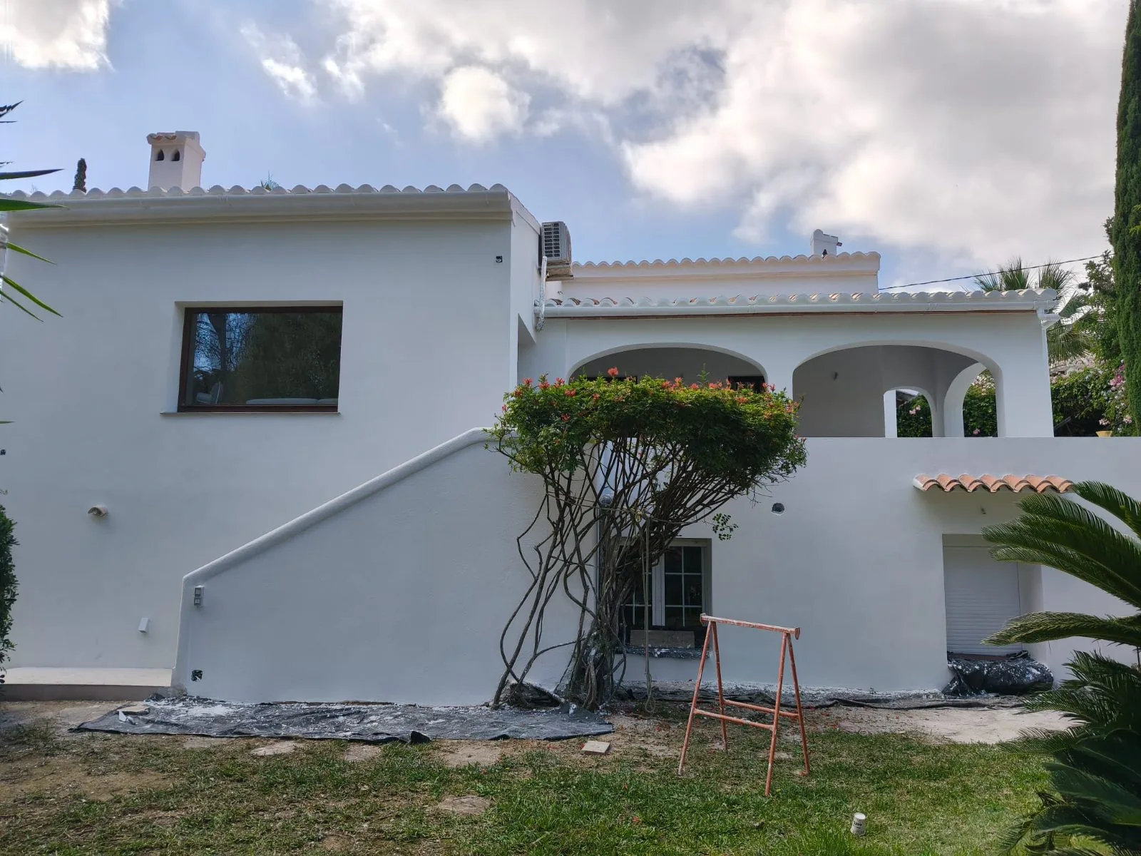 Vivienda con fachada recién pintada de blanco, escalera exterior y porche con arcos