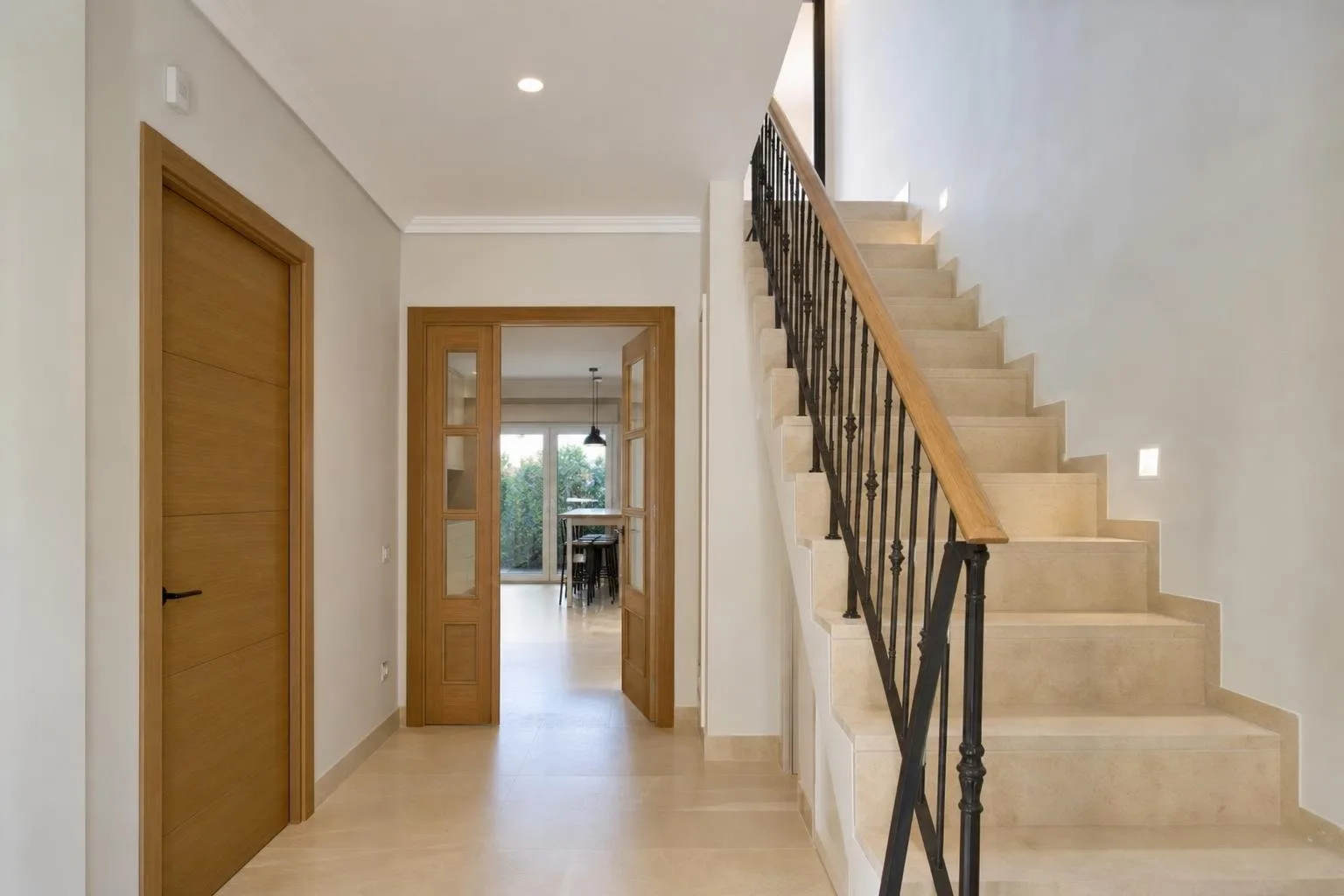 Recibidor y escalera de una vivienda reformada con suelo de piedra clara